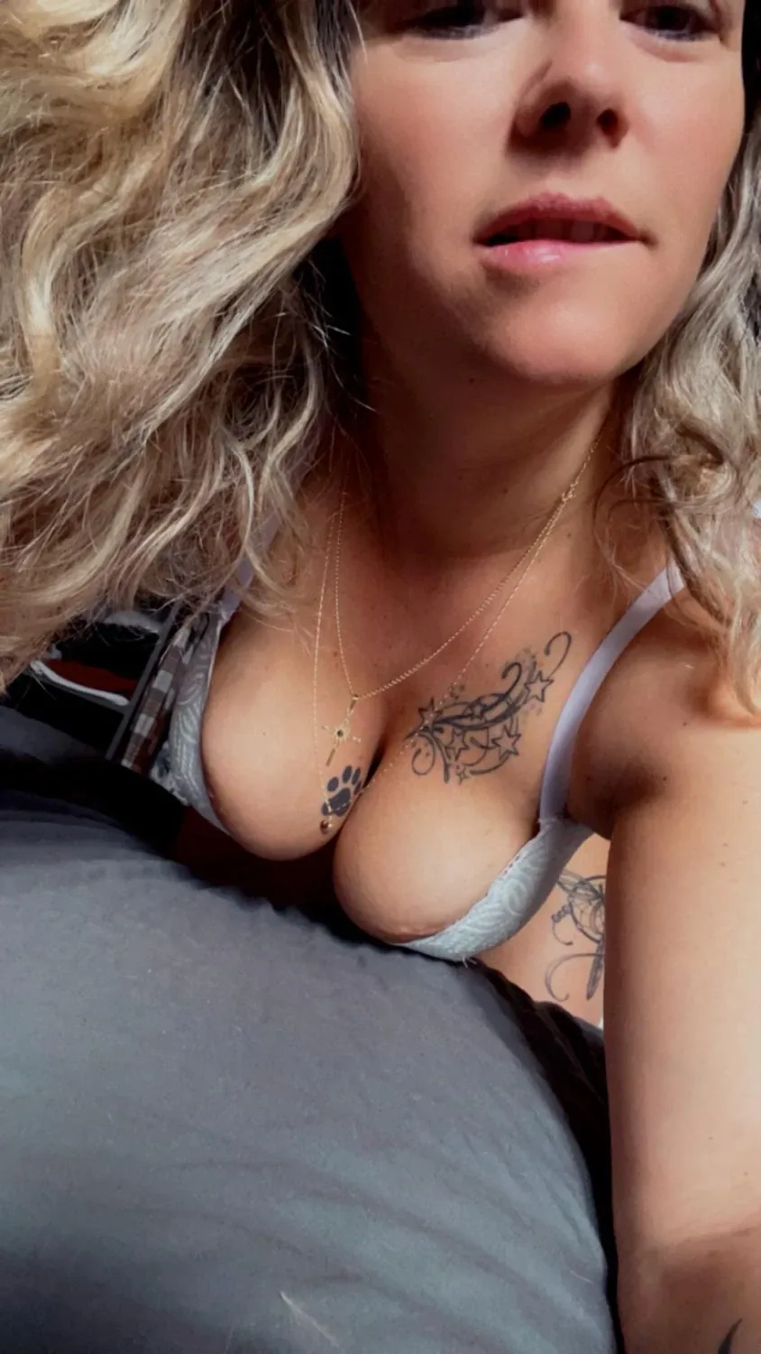 Bella_gwen close-up selfie in a white bra, curly blonde hair and a star tattoo
